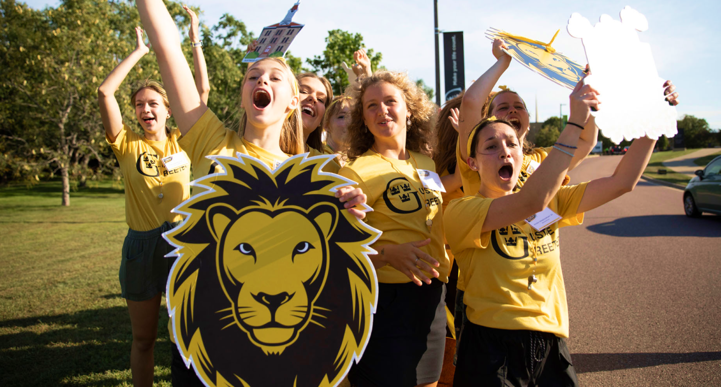 Students cheering with Gustavus lion mascot sign